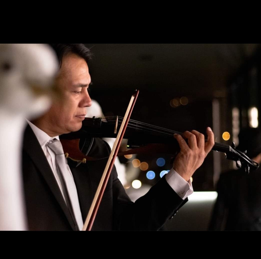 El maestro Patricio Mora interpretando el violín durante un evento nocturno